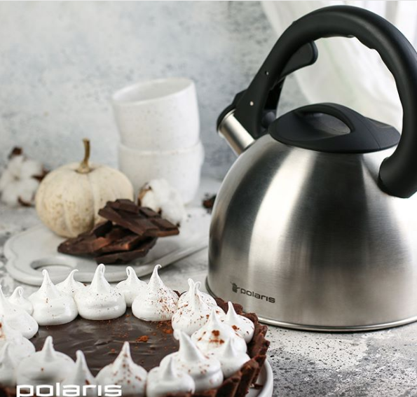 Чайник Polaris, торт, плитки шоколада и чашки стоят на столе